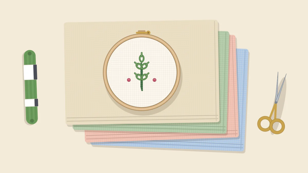 A stack of four folded fabrics in neutral and soft colors with a small embroidery hoop resting on top