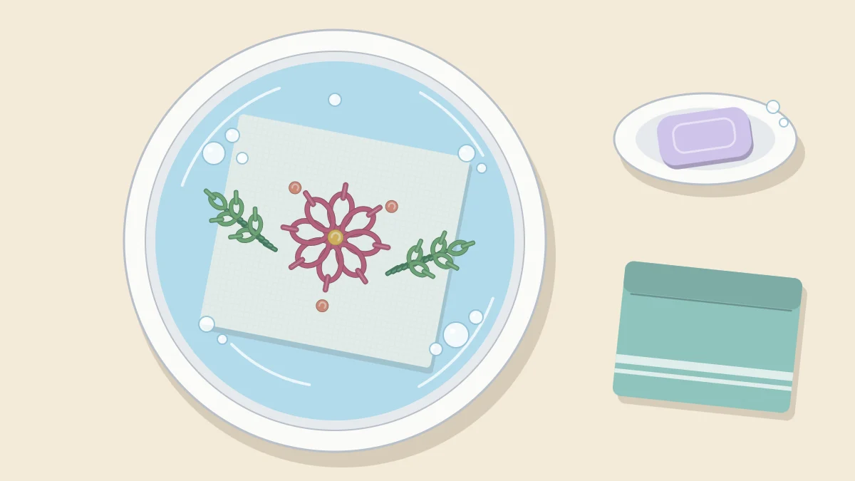 Embroidered cloth soaking in a basin of water with a few soap bubbles on the surface
